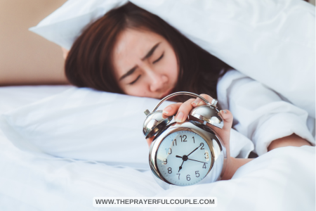 woman sleeping with hand on alarm clock